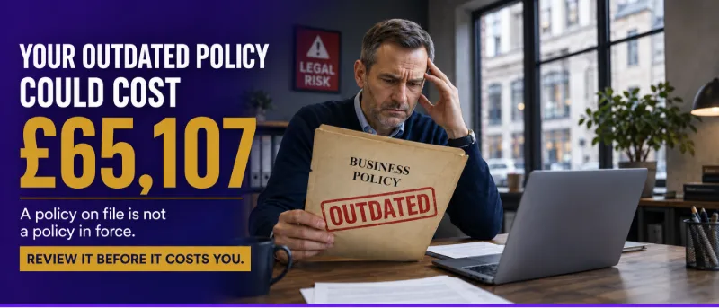 A business owner reviewing printed policies beside a laptop and compliance checklist in a modern office.